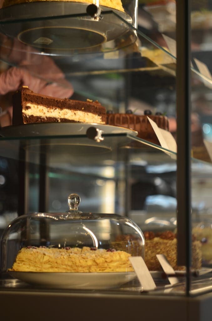 Tempting variety of cakes displayed in a glass case at a bakery.