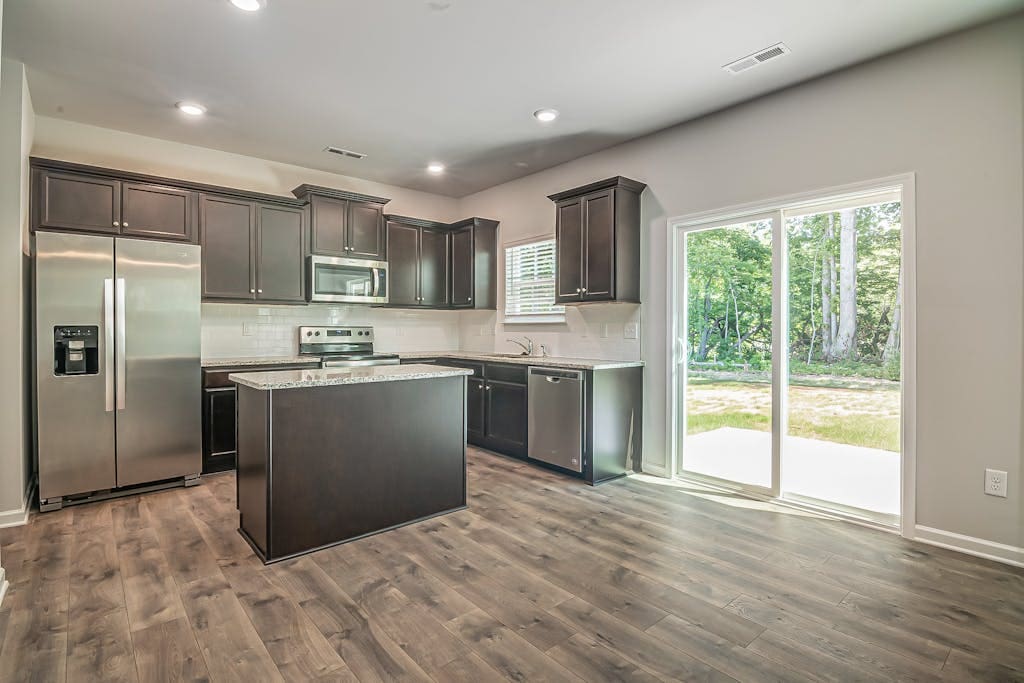 Spacious modern kitchen with stainless steel appliances and wooden floors.