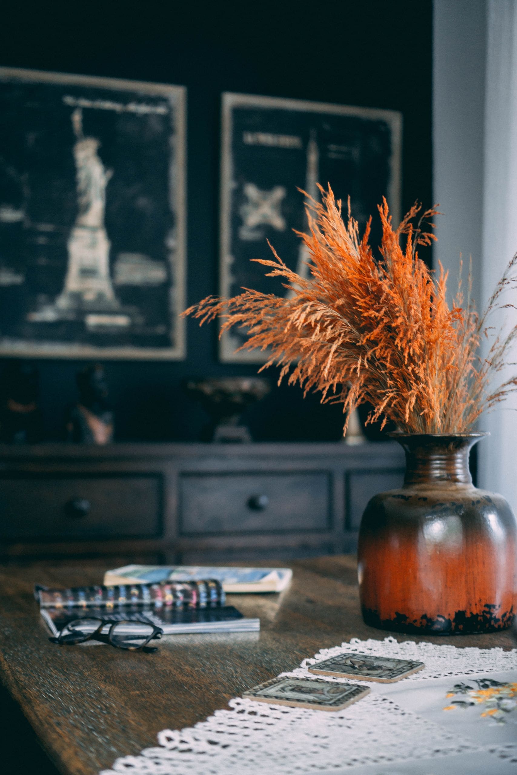 Warm and inviting autumn setting with a rustic vase filled with wheat, cozy decorations, and books.